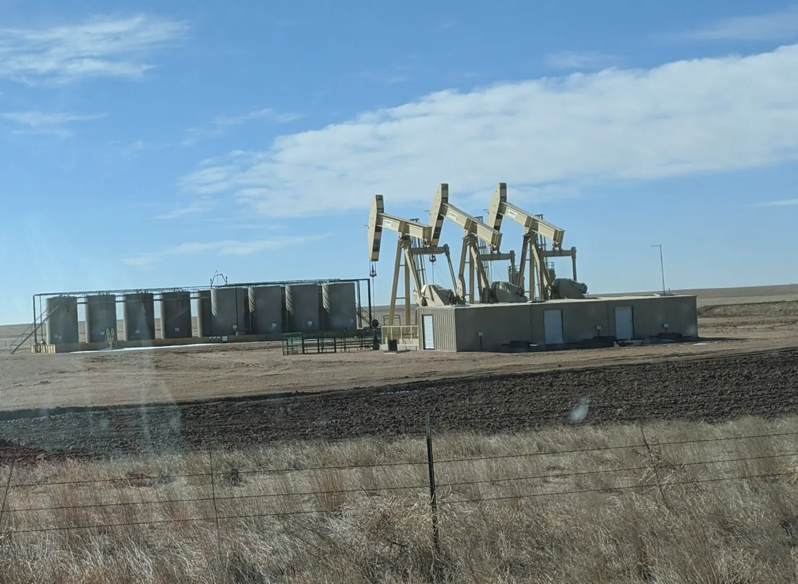 Rockies and DJ Basin in Colorado and Wyoming: pumpjacks and storage tanks at an oil well site beside Colorado Highway 14 near the Pawnee National Grassland