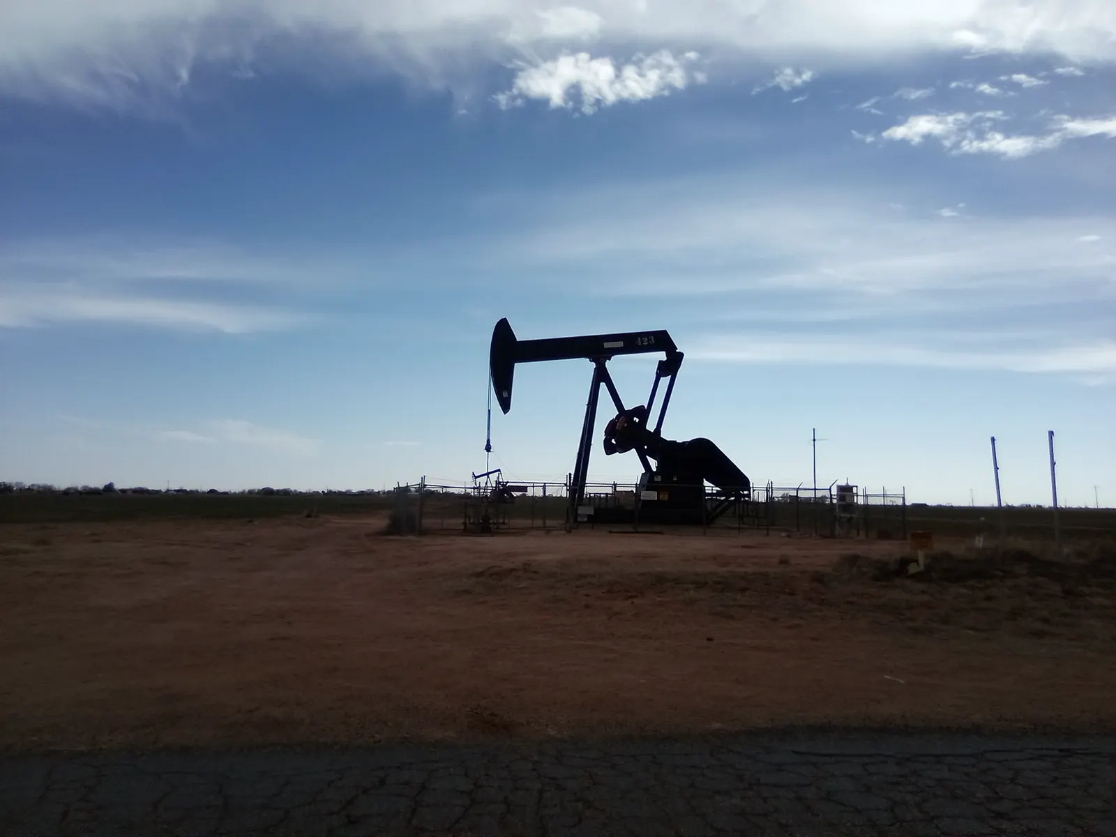 Permian Basin in Texas and New Mexico: a pumpjack silhouetted against a wide sky on red dirt near Levelland, Texas